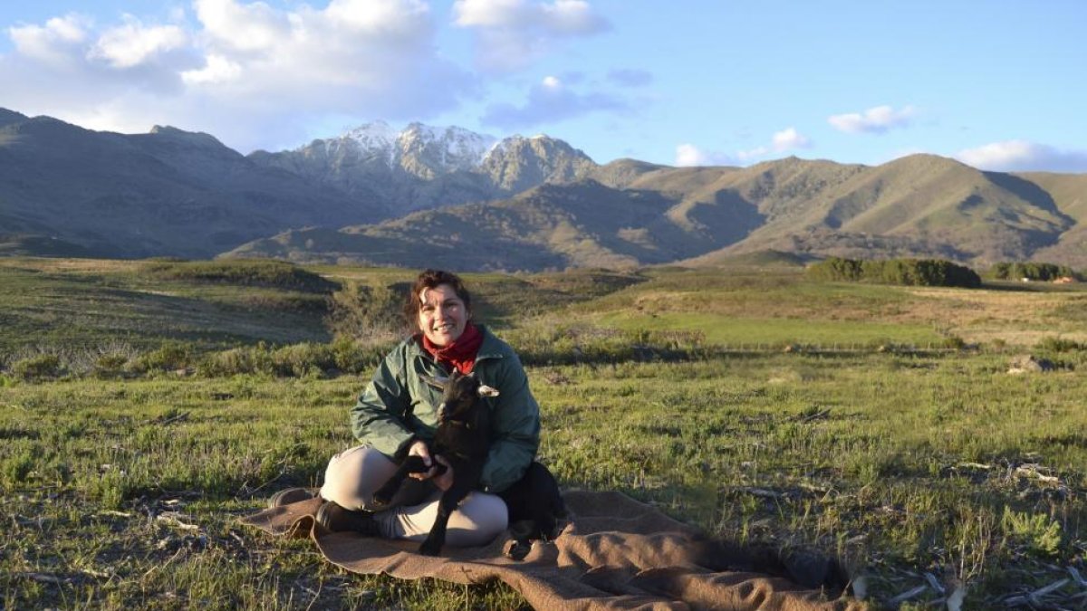 Maribel Sánchez, con uno de sus cabritos, en el lugar donde pastan sus animales, en el Valle del Tiétar (Ávila); al fondo, la Sierra de Gredos.-ARGI
