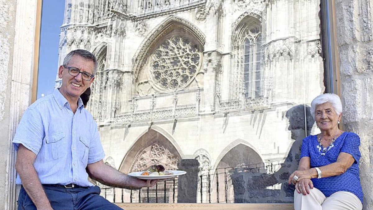 María Luisa Pascual y su hijo José Luis, en uno de los ventanales del Mesón del Cid, donde se refleja la fachada de la Catedral de Burgos.-ARGICOMUNICACIÓN