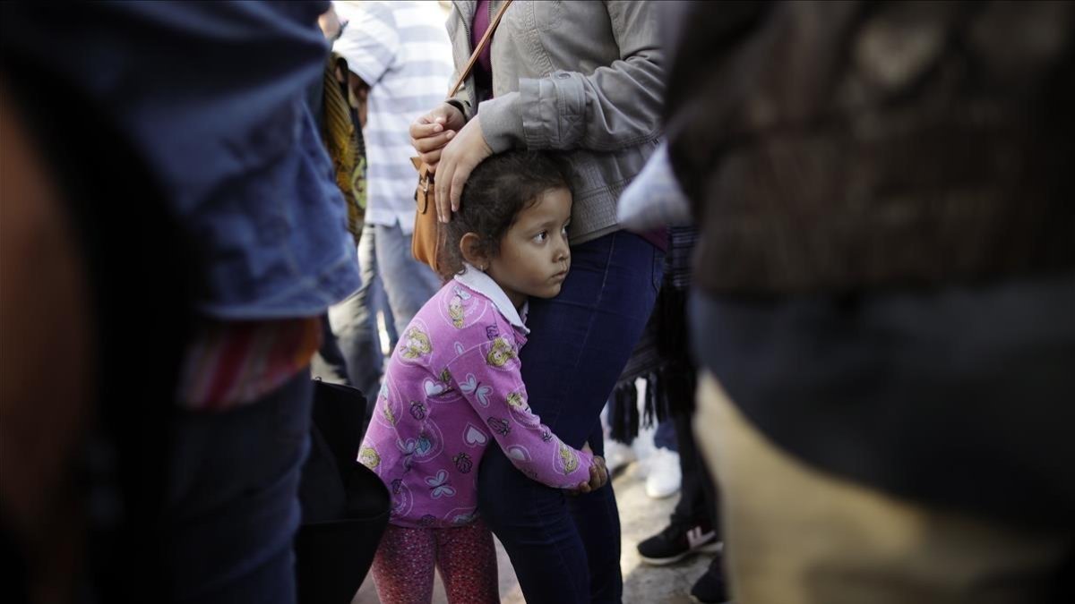 Una niña mexicana con su madre espera con otros inmigrantes en la frontera la respuesta a la solicitud de asilo político en EEUU.-AP / GREGORY BULL E
