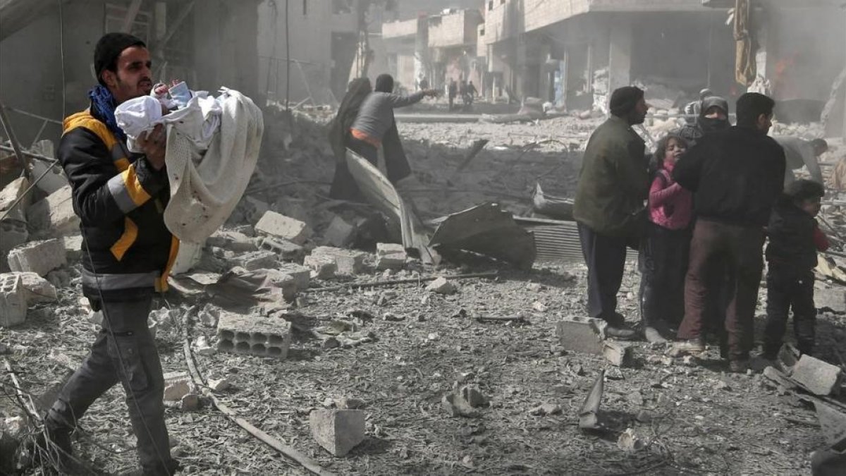 Un hombre lleva en brazos a un bebé rescatado entre las ruinas de un edificio tras el bombardeo de Guta por parte de las fuerzas del régimen de Damasco.-AFP / ABDULMONAM EASSA