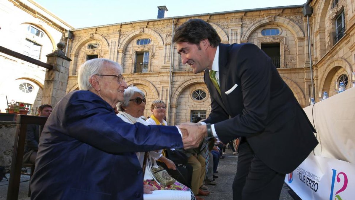 El consejero de Fomento y Medio Ambiente de la Junta, Juan Carlos Suárez-Quiñones Quiñones (D), saluda a Cristóbal Halfter, elegido Hijo Predilecto del Bierzo durante el acto de aniversario de la Constitución del Consejo Comarcal del Bierzo.-ICAL