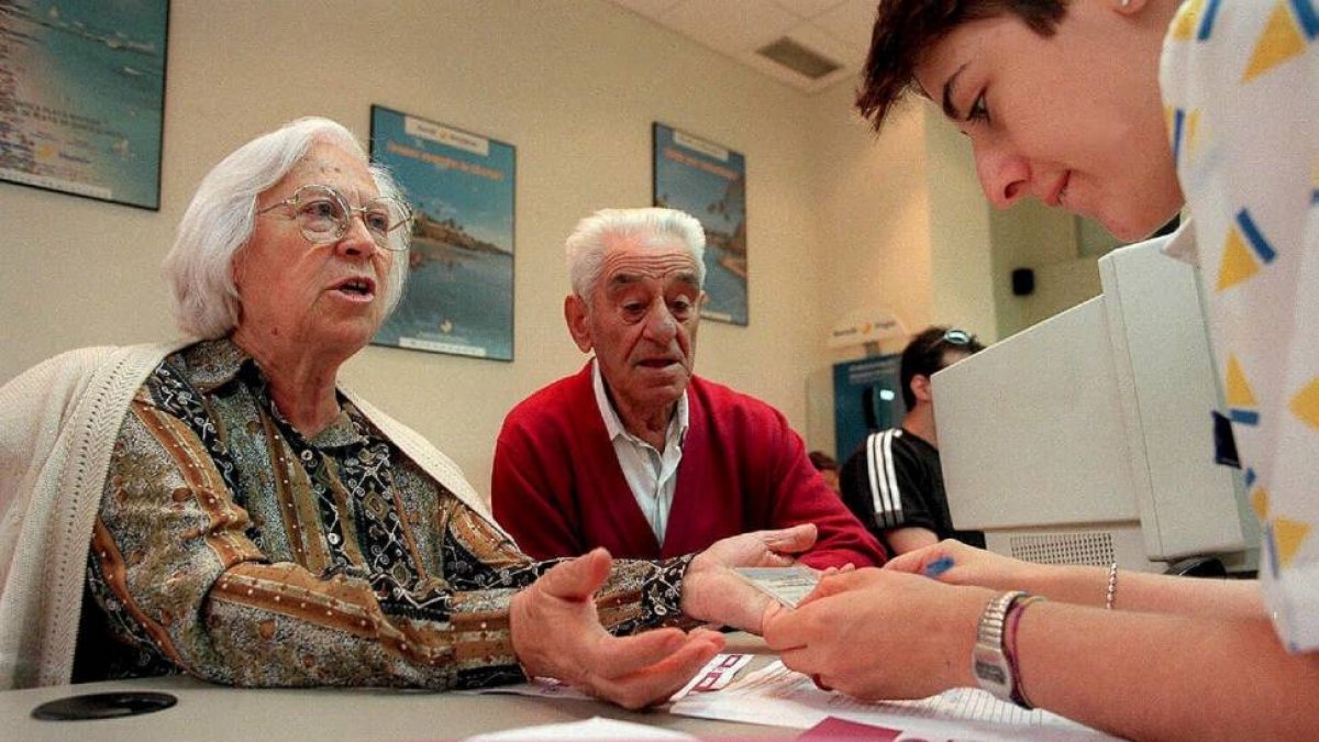 Dos jubilados contratan su viaje del Imserso de una temporada anterior en una agencia de viajes .-B. Cordon