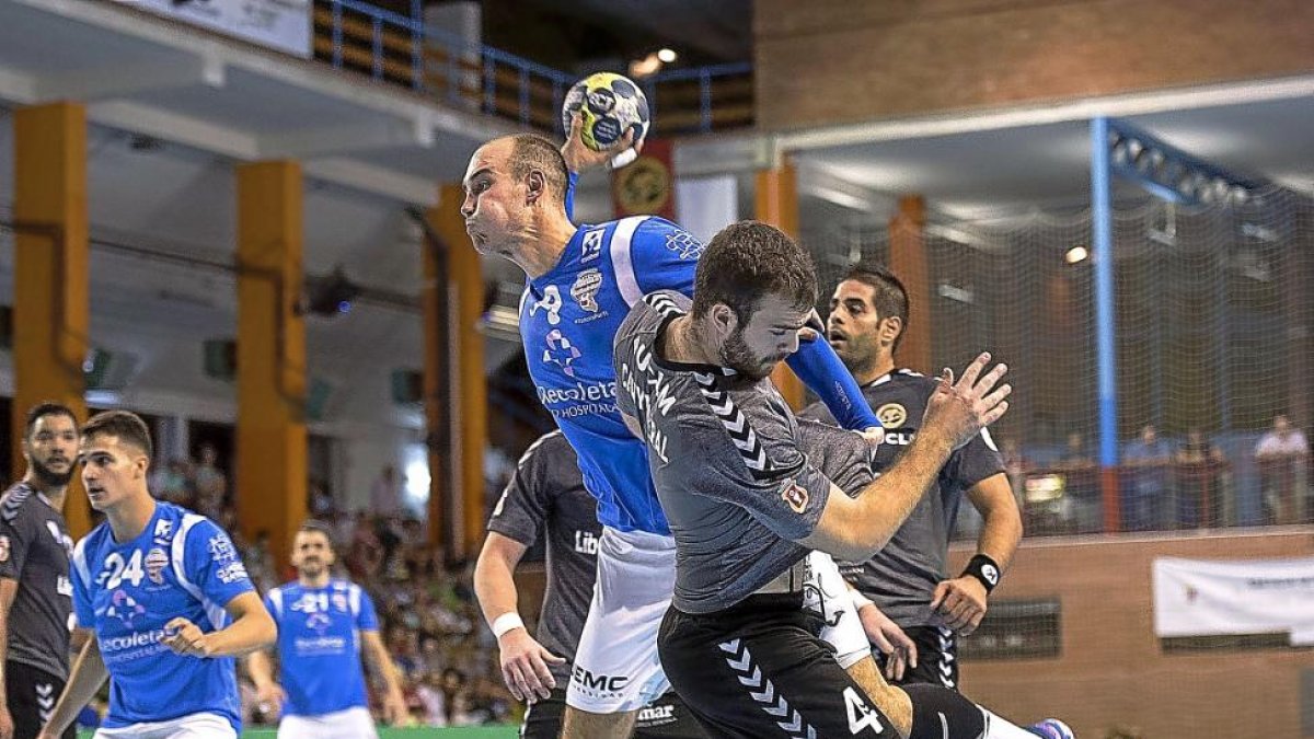 El central Adrián Fernández a punto de lanzar tras chocar con el defensor rival Marc Canyigueral.-PHOTO-DEPORTE