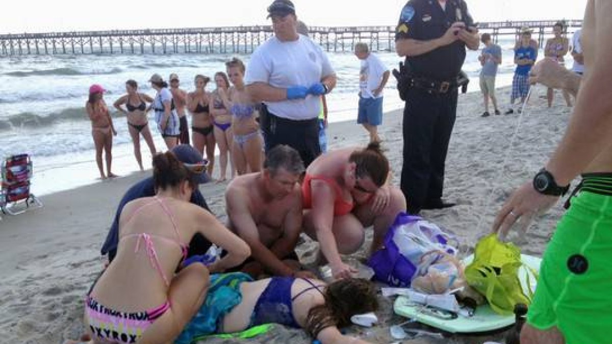 Los servicios de emergencia atienden a la joven de 14 años que ha sido atacada por un tiburón, este domingo en la playa de Oak Island.-Foto:  AP / STEVE BOUSER