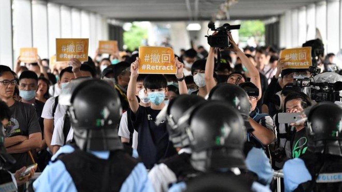 Un grupo de manifestantes sostienen pancartas de protesta contra la policía hongkonesa, este jueves.-EDWIN KWOK (EFE)