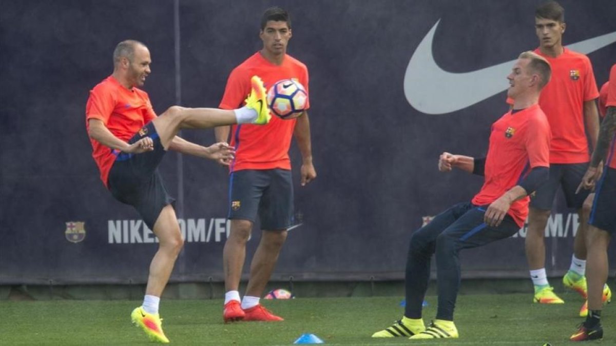 Iniesta golpea el balón ante Suárez y Ter Stegen durante la sesión de entrenamiento de este lunes-JORDI COTRINA