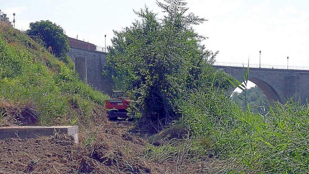 Una grúa se abre camino por la ribera del río Duero al pie del puente medieval, ayer en Tordesillas.-EL MUNDO