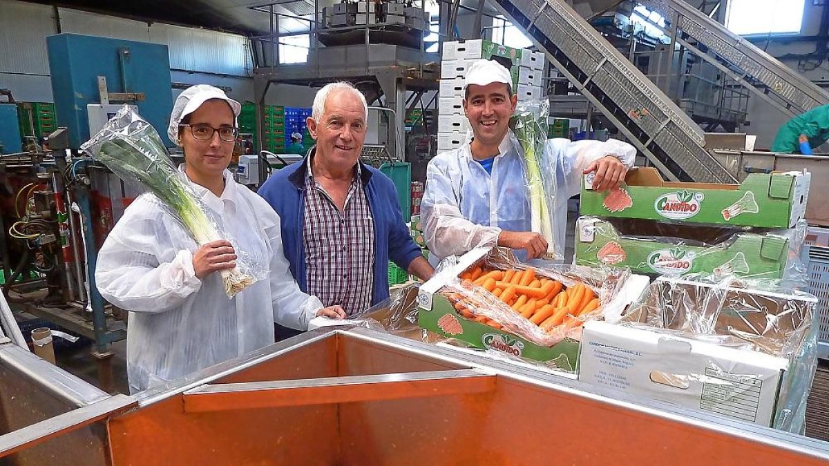 Marta y David posan junto a su padre, Cándido Muñoz, entre puerros y zanahorias.-T. S.