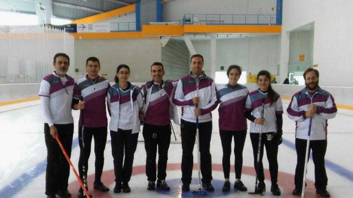 Varios de los integrantes de HieloPisuerga posan con sus escobas sobre una pista de curling.-R. GRÁFICO: M.R. HENARES