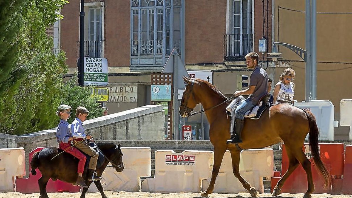 Un hombre a lomos de un caballo contempla a dos niños montados en un poni durante la mañana de ayer en Rioseco.-PABLO REQUEJO