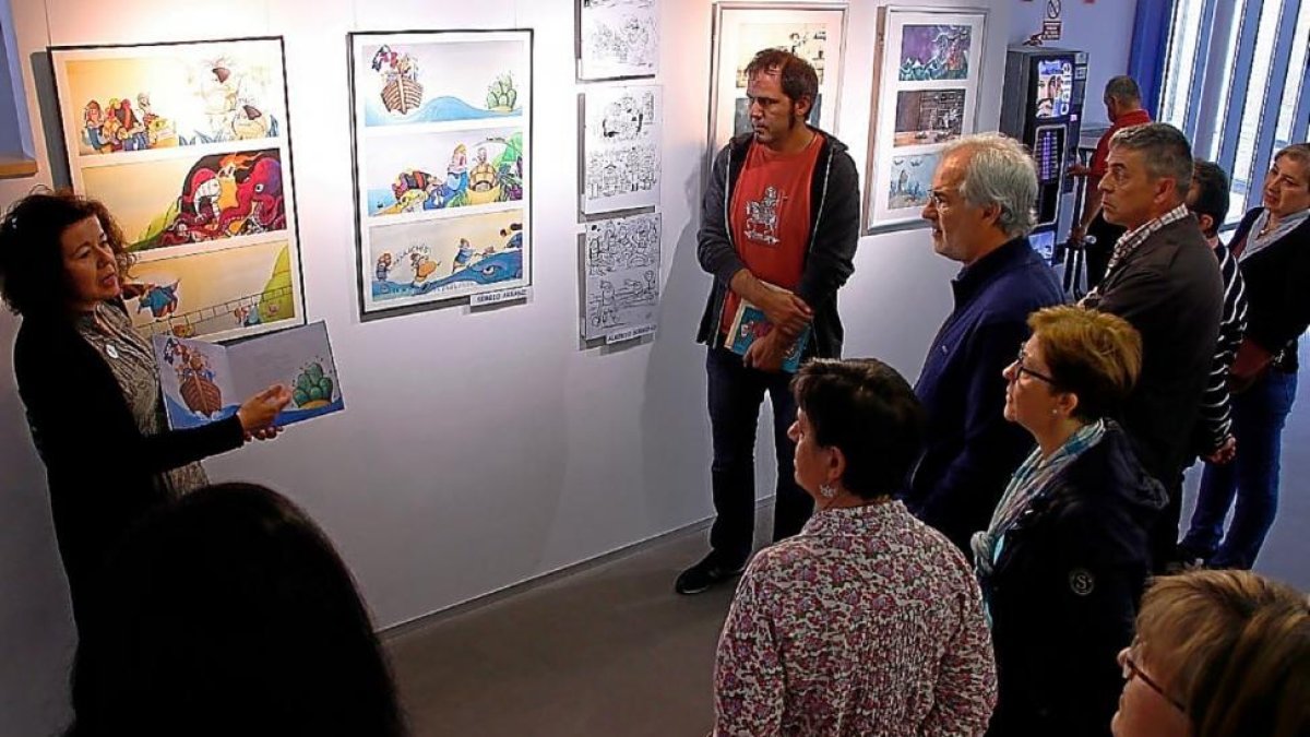 Varias personas observan una de las exposiciones de Ilustralaguna 2017,-EL MUNDO
