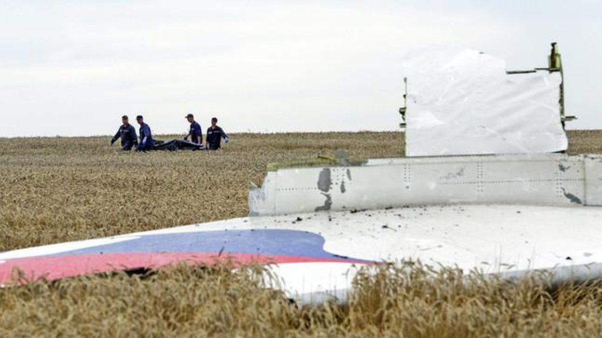 Varias personas transportan un cadáver en una camilla en medio de los destrozos de un Boeing 777, vuelo MH17 de Malaysia Airlines, derribado cerca de Donetsk (Ucrania).-EFE / ANASTASIA VLASOVA