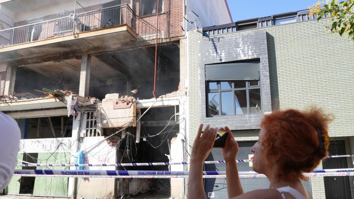 Una mujer fotografía el edificio siniestrado.- J. M. LOSTAU