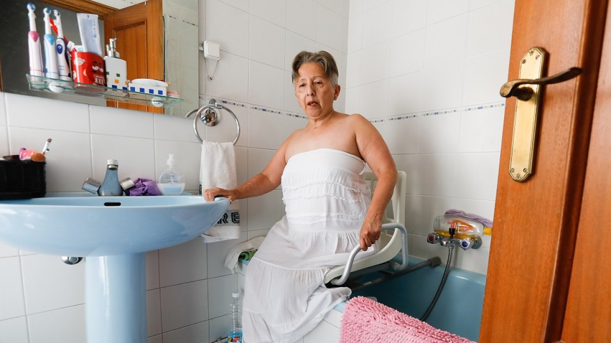 Juana Macay, en el baño de su casa, con los aparatos adaptados para el aseo. / J.M. LOSTAU