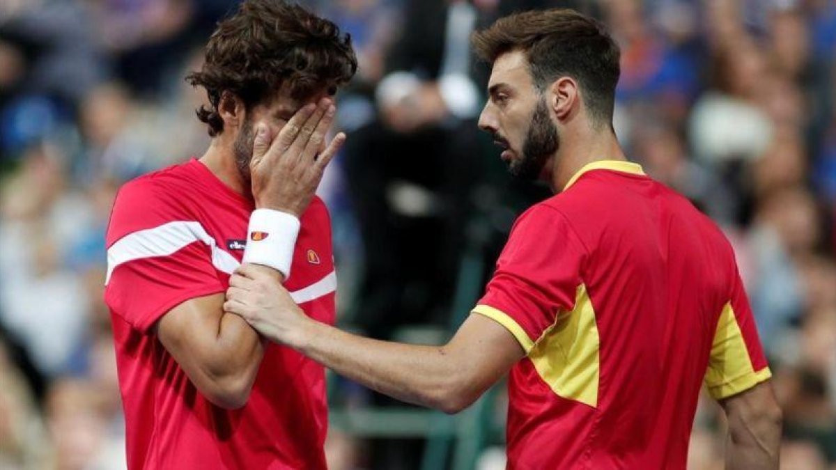 Feliciano López se toca la cara tras recibir el impacto de una bola, junto a Granollers, en Lille.-BENOIT TESSIER (REUTERS)