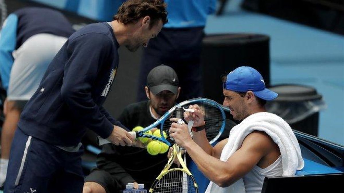 Nadal pone cinta en su raqueta ante la presencia de su entrenador, Carlos Moya.-