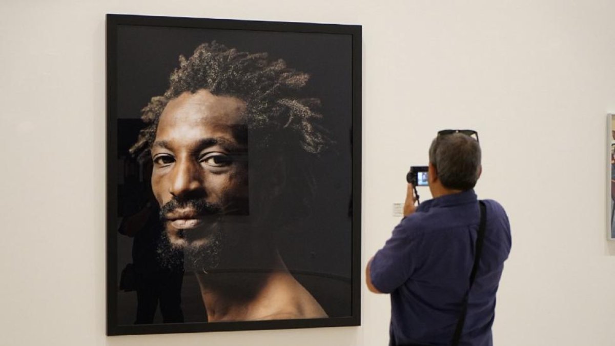 Una hombre fotografía un retrato de Pierre Gonnord.-C.A.