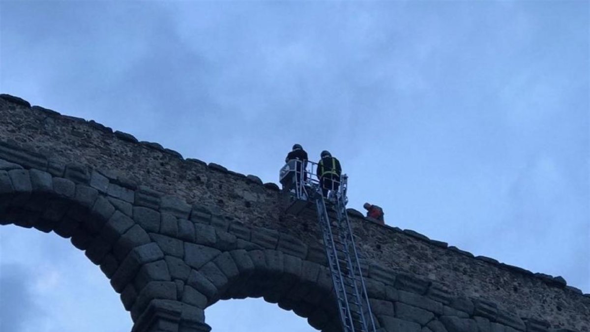 Los bomberos, en plena intervención en lo alto del acueducto.-E.M.
