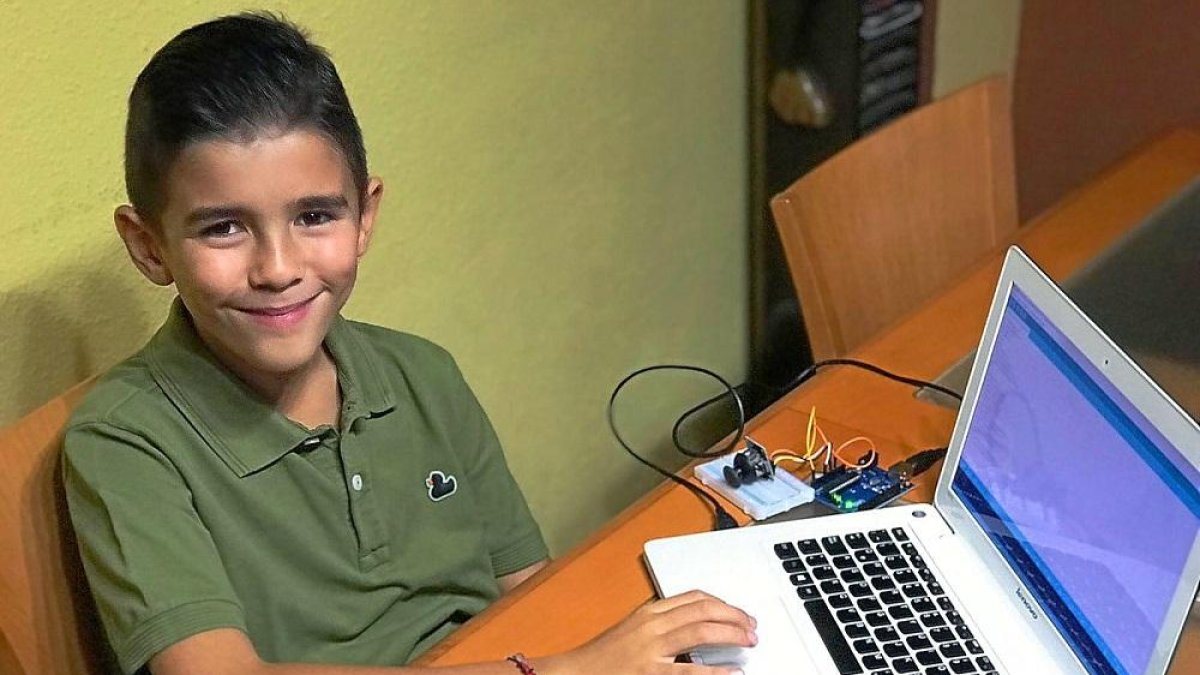 El joven vallisoletano Antonio García posa con un ordenador portatil y un robot.-EL MUNDO