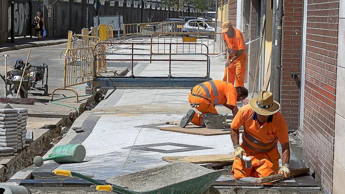 Los operarios trabajan para renovar el asfalto y colocar las baldosas en la calle Estación.-P. REQUEJO
