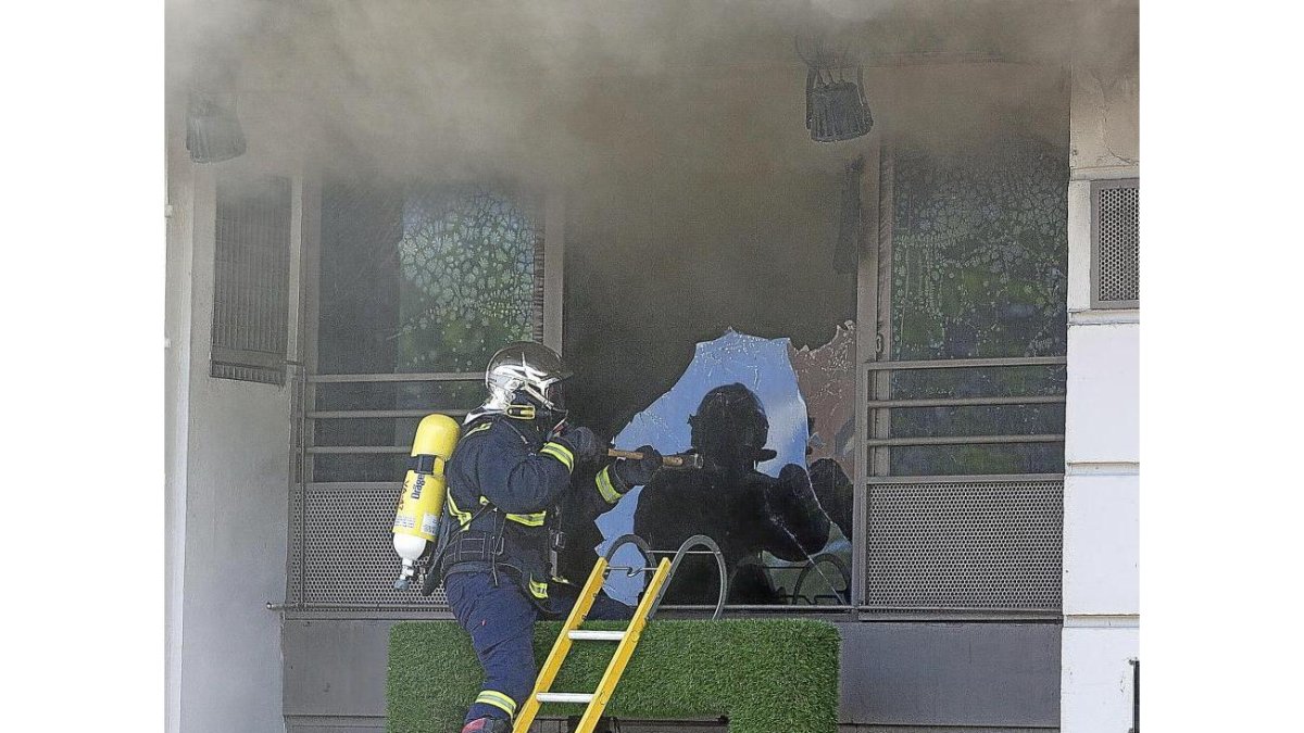 Un bombero rompe el cristal de la entreplanta del bar para poder soficar el incendio.-Pablo Requejo