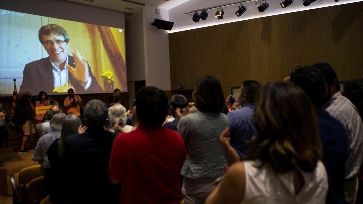 Carles Puigdemont saluda, a través de una pantalla, a los asistentes a la presentación de Crida Nacional per la República-EFE / QUIQUE GARCÍA