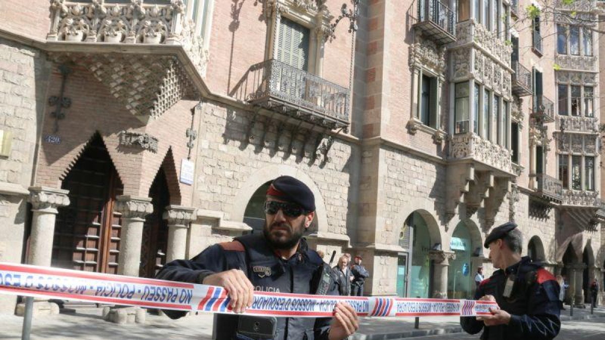 Dos agentes de los Mossos acordonan la zona mientras la Guardia Civil inspecciona la sede del Diplocat, durante un registro el pasado 12 de abril.-ALAN RUIZ TEROL (ACN)