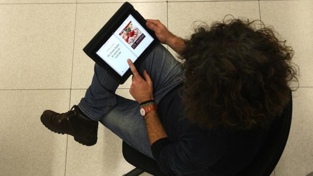 Una lectora, consultando un libro de recetas en una tablet.-ELISENDA PONS