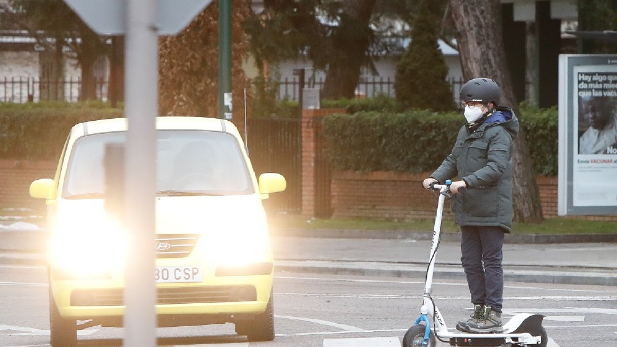 Un joven con un patinete cruza un paso de peatones en una calle de Valladolid. J.M. LOSTAU
