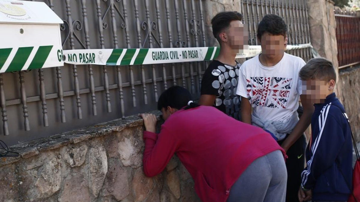 Unos vecinos miran hacia el interior de la casa donde aparecieron los cuerpos-EL MUNDO