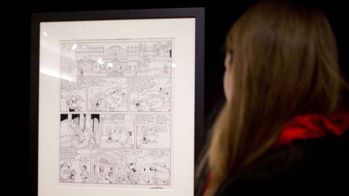 Una mujer mira la plancha de Astérix subastada a beneficio de los familiares de los dibujantes de 'Charlie Hebdo'.-Foto: AFP / KENZO TRIBOUILLARD