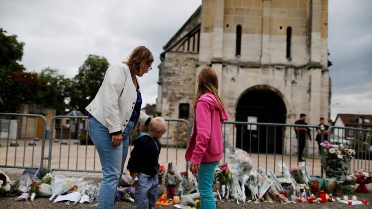 Una madre y sus hijos dejan flores ante la iglesia de Saint-Etienne-du-Rouvray.-CHARLY TRIBALLEAU / AFP
