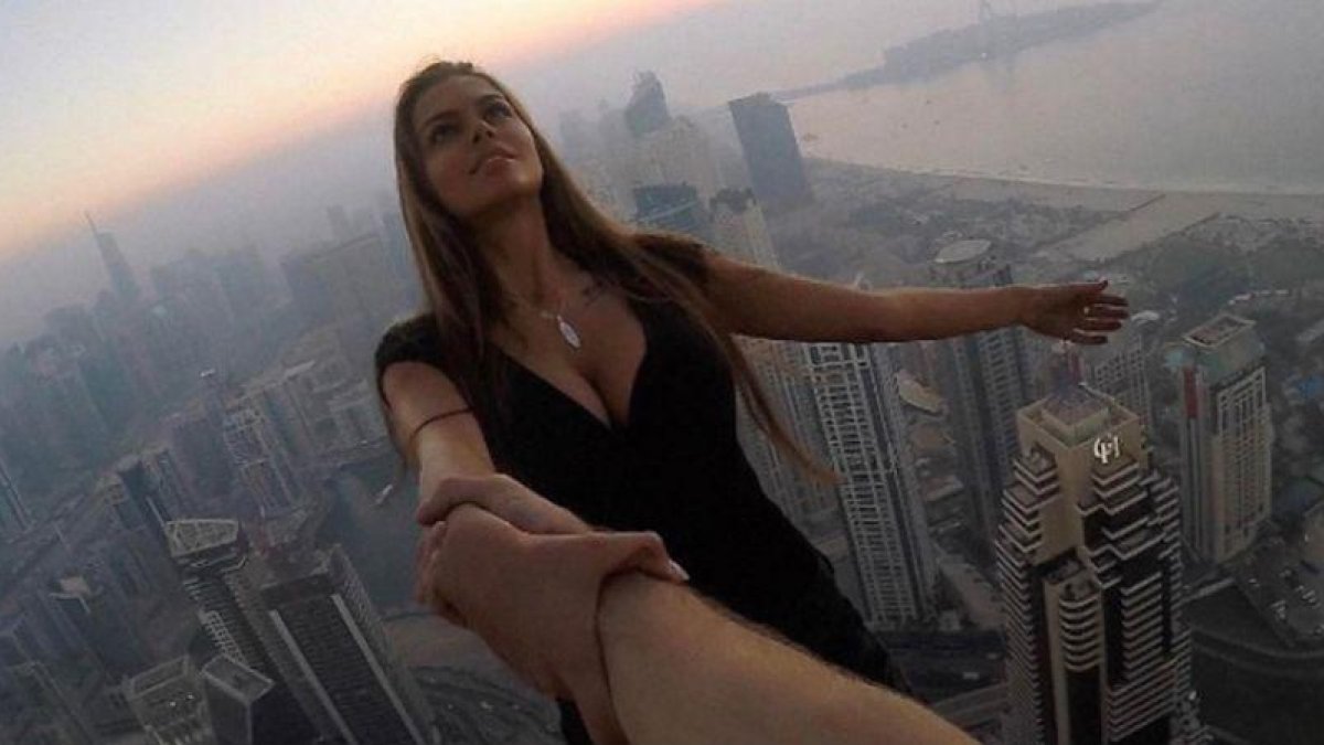 Viki Odintcova, de la mano de su asistente, sin arnés, a 300 metros de altura, a punto de hacerse un selfi de vértigo.-