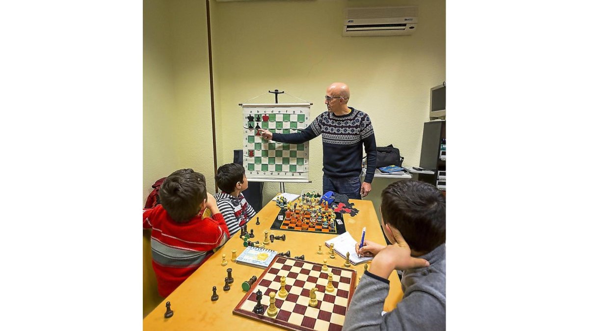 El profesor Fernando les enseña algunas jugadas para que den jaque mate en una partida, mientras algunos de los chavales apuntan las técnicas en un cuaderno.-MIGUEL ÁNGEL SANTOS