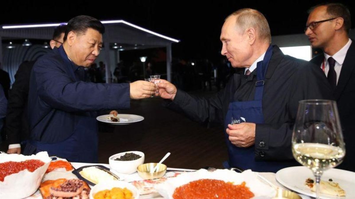 El presidente ruso, Vladimir Putin, brinda con su homólogo chino, Xi Jinping, en una feria alementaria en Vladivostok.-AFP / SERGEI BOBYLYOV