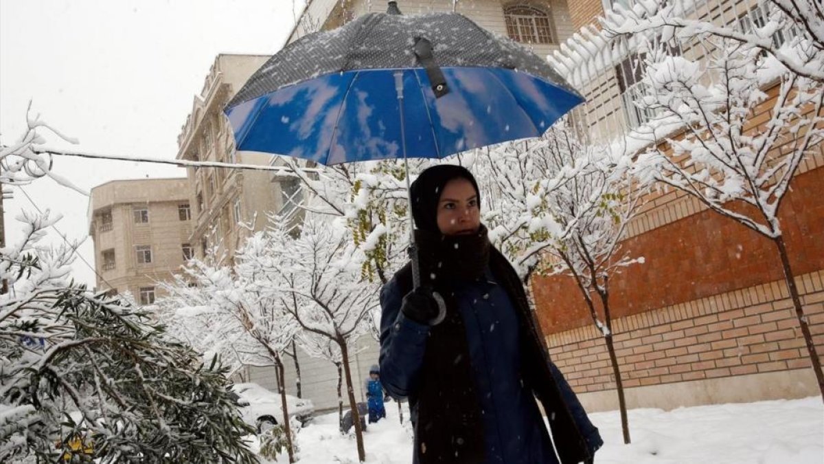 Una mujer iraní pasea por una calle nevada, en Teherán, el 28 de enero.-EFE / ABEDIN TAHERKENAREH