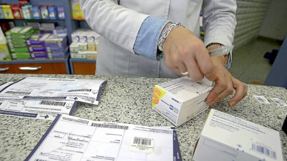 Una farmacéutica recorta el identificador del medicamento.-Ical