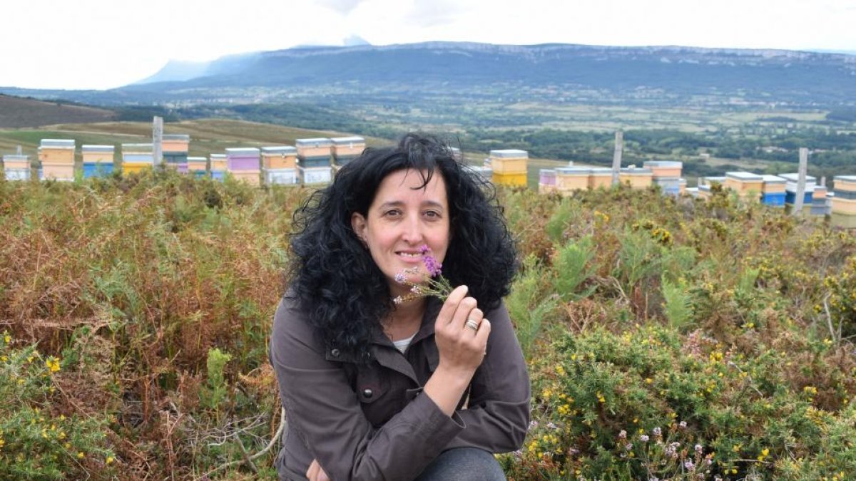 La apicultora burgalesa Yolanda Martínez, en un prado de La Sía, frente a una cabaña de pastores pasiegos con dujos -colmenas en las cortezas de árbol- a la puerta.-ARGICOMUNICACIÓN
