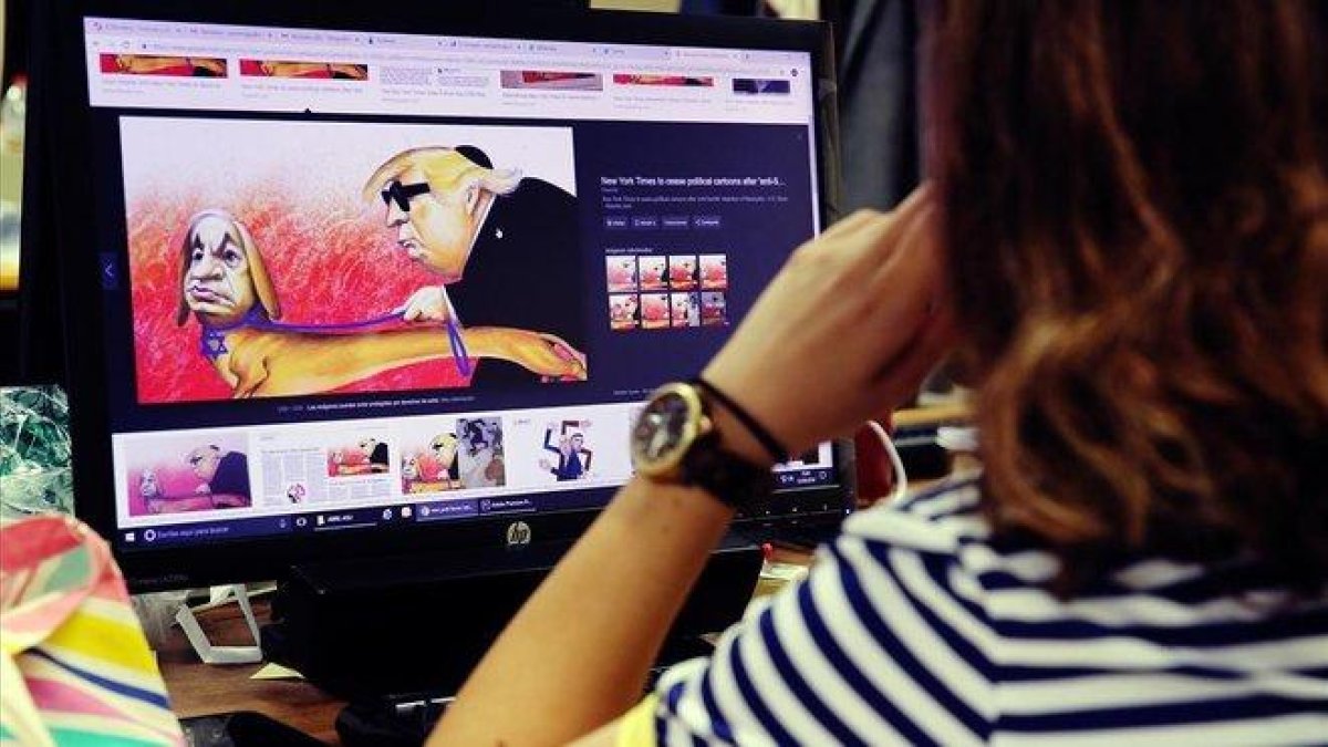 Una mujer mira la polémica caricatura de Netanyahu y Trump que ha llevado a The New York Times a suprimir las viñetas políticas en su edición internacional.-RICARD CUGAT