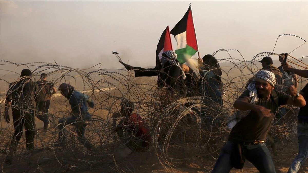 Manifestantes palestinos lanzan piedras contra los soldados israelís en las protestas de este viernes en Khan Younis, en el sur de la frontera de Gaza.-AP / ADEL HANA