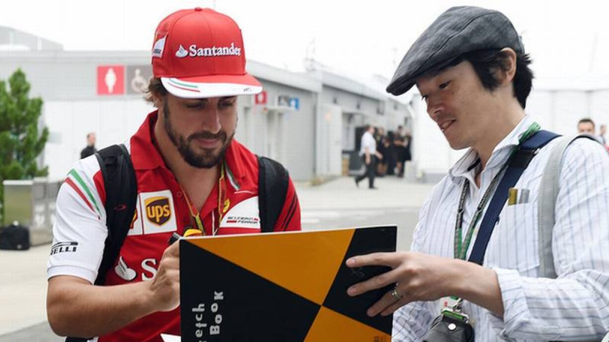 Fernando Alonso firma un autógrafo a un fan en el circuito de Suzuka.-Foto: AFP / TOSHIFUMI KITAMURA