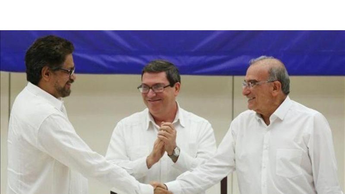 A la izquierda, el líder del equipo negociador de las FARC, Iván Márquez, se da la mano en La Habana con el representante gubernamental, Humberto de la Calle.-ALEXANDRE MENEGHINI / REUTERS