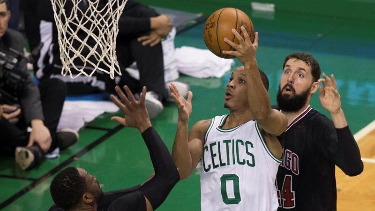 El jugador de Celtics Avery Bradley (c) se dirige a canasta ante la marca de Dwyane Wade (i) y Nikola Mirotic (d), de los Bulls.-EFE