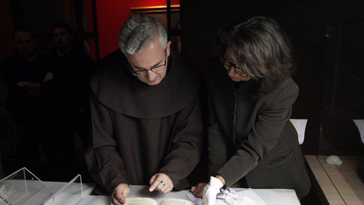 El Padre Juan Dobado, comisario de la exposición 'Teresa de Jesús, La prueba de mi verdad' y la restauradora, Charo Fernández, examinan la segunda redacción del manuscrito autógrafo de La Santa 'Camino de perfección'-Ical