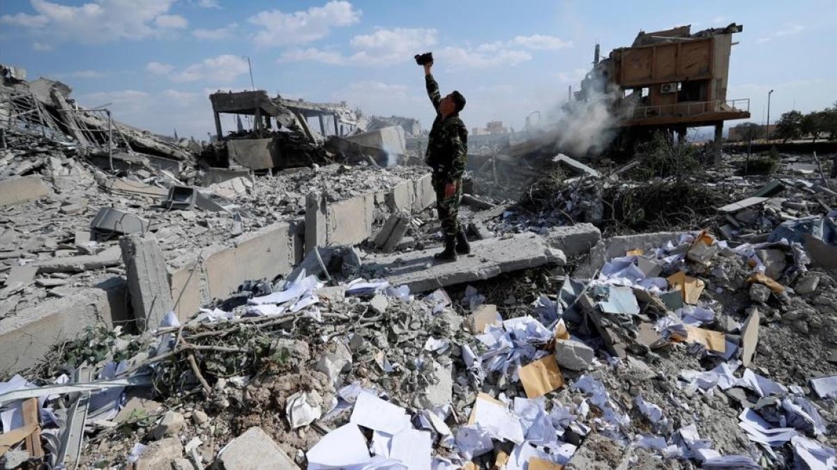 Un soldado sirio filma los escombros tras un ataque de las fuerzas estadounidenses, francesas y británicas el 14 de abril del 2018 para castigar al presidente Bashar el Asad por el uso de armas químicas contra civiles.-/ HASSAN AMMAR (AP)