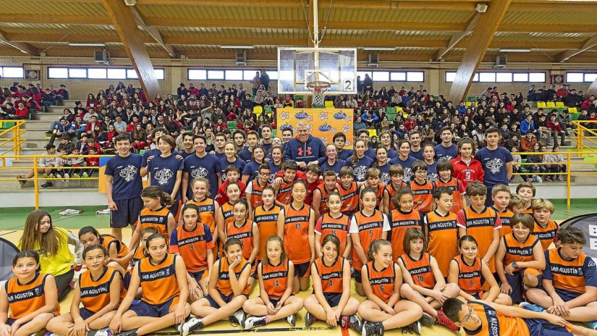 Participantes del colegio San Agustín en la Copa Colegial posan con el ex jugador norteamericano Joe Arlauckas con una grada del pabellón completa.-MIGUEL ÁNGEL SANTOS