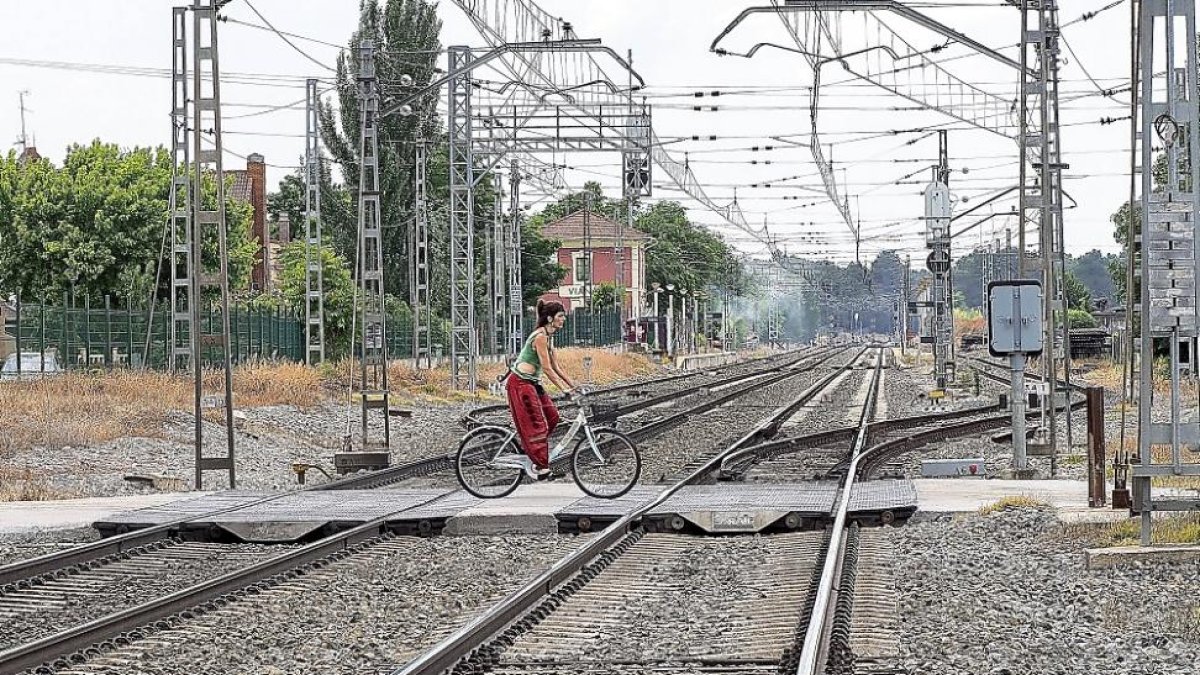 Una joven atraviesa las vías en bicicleta.-MIGUEL ÁNGEL SANTOS