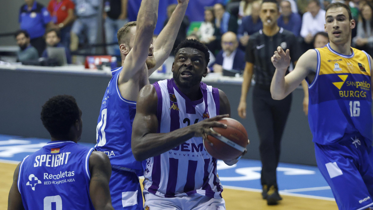 Nwogbo mira la canasta ante la oposición por detrás de Fischer.