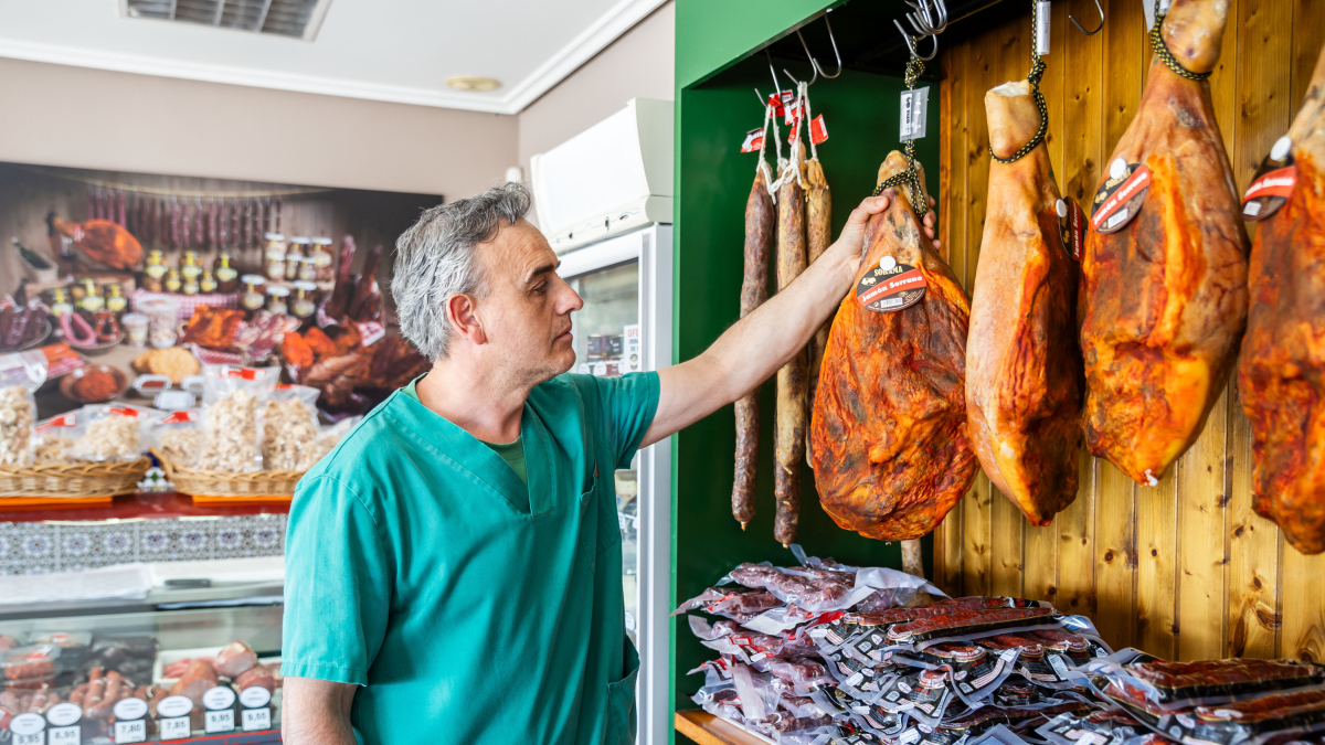 Santiago Alonso observa uno de los jamones con su característico pimentonado, tradicional de la zona y que da a las piezas un aspecto característico.