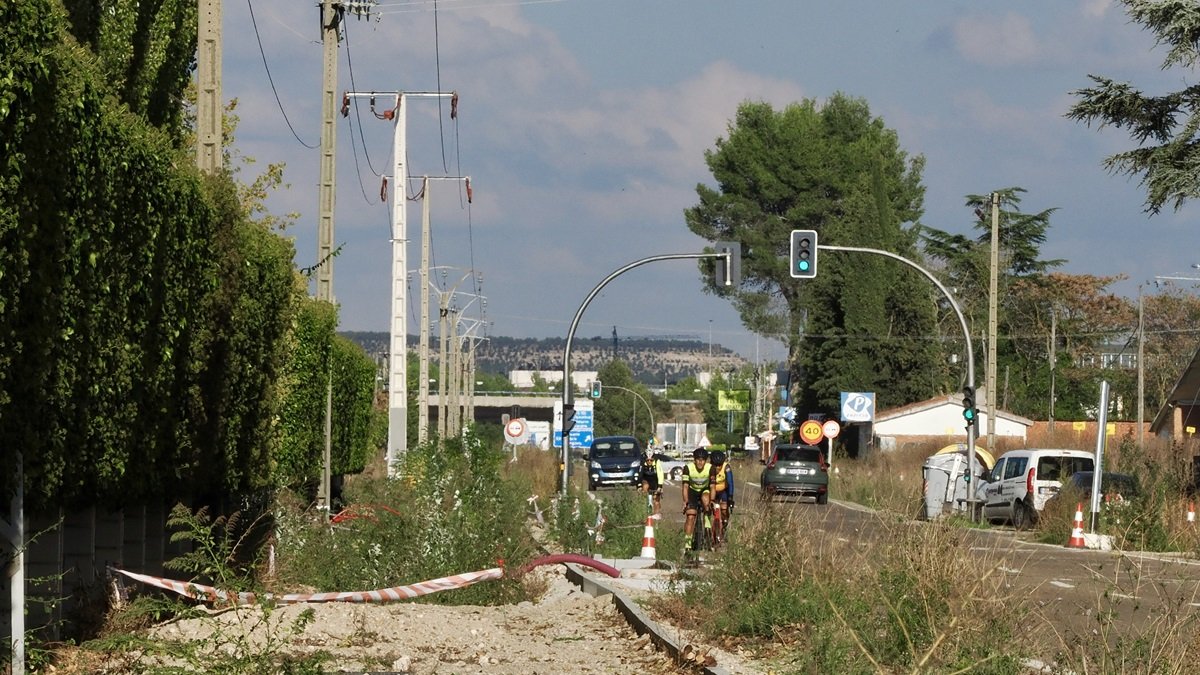 Dos ciclistas circulan por la calzada, junto a las obras inacabadas del carril bici.